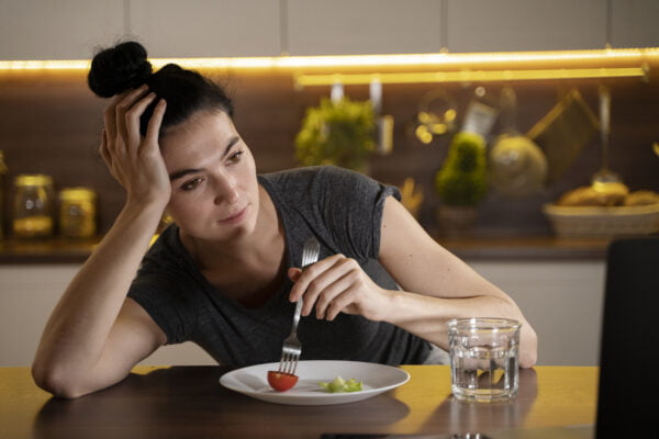Freepik Imagem: Mulher tentando comer saudável em casa