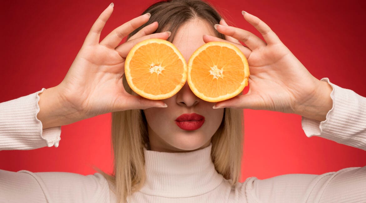 Freepik imagem Mulher segurando fatias de laranja sobre os olhos